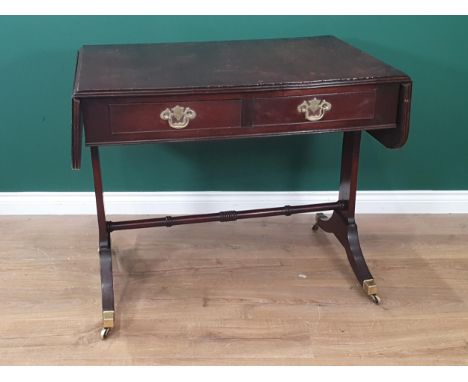 A Regency mahogany Sofa Table fitted two drawers on cheval frame with down swept feet having brass toe caps and casters