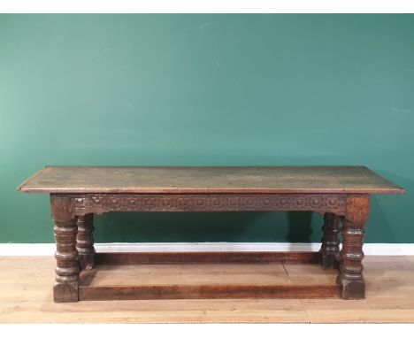 A 17th Century oak Refectory Table with cleated thick three plank top above carved frieze to one side, on massive ring turned
