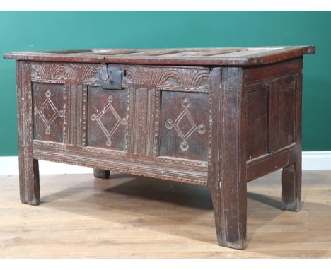 A 17th Century oak Coffer with four sunken panel lid, above carved floral arch frieze and lock plate and three diamond design