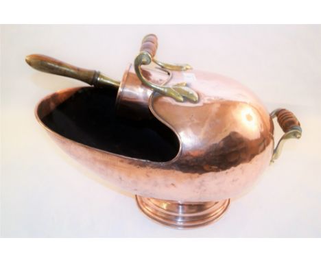 A large helmet shaped copper coal scuttle with shovel