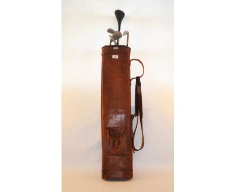 A vintage leather golf bag with five clubs