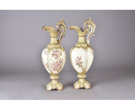 A pair of 19th Century continental porcelain ewers, ovoid lobed bodies with floral sprays heightened in gilt, bracket feet hi