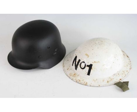 A reproduction German M 1935 steel helmet with leather liner, together with a post WW II white painted Brodie helmet and thre