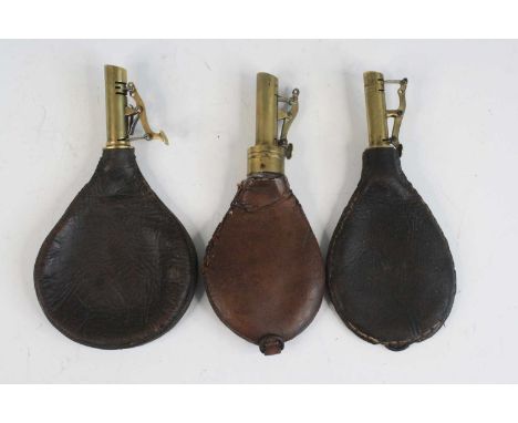 A 19th century leather shot flask, of typical pear shape, the brass nozzle measuring 1 to 1 1/4 oz, 20cm, together with two o