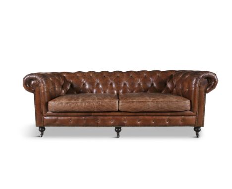 A CHESTERFIELD SOFA,upholstered in button back brown hide, fitted with two loose seat cushions on short turned legs and casto