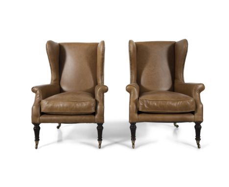 A PAIR OF REGENCY CLOSE NAIL WINGBACK ARMCHAIRS, each upholstered in light brown/beige leather, raised on carved mahogany lot