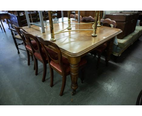 A LATE VICTORIAN OAK OBLONG EXTENDING DINING TABLE WITH TURNED AND FLUTED SUPPORTS, ORIGINAL CERAMIC CASTORS AND THE EXTENSIO