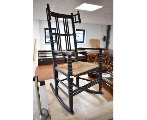 A Victorian dark stained rocking chair having bobbin turned frame and rush seat