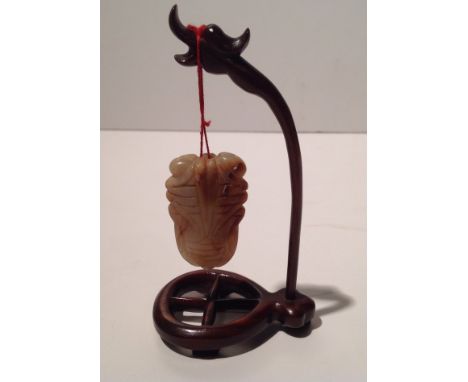 AN ANTIQUE CHINESE MUTTON FAT JADE PENDANT Supported on a hardwood stand.  (5cm x 3cm)