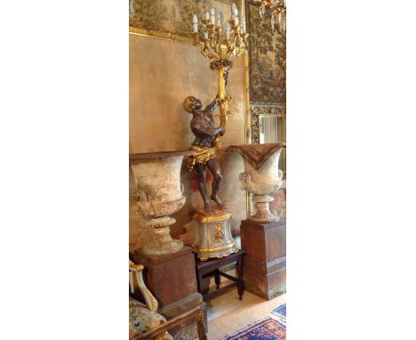 A DECORATIVE COMPOSITE FIGURAL LAMP Formed as a semiclad Nubian, holding a nine branch candelabra aloft. 