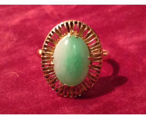 A 22CT GOLD AND OVAL JADE CABOCHON RING Claw set into a pierced surround. 