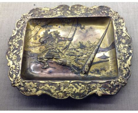 A 19TH CENTURY ORIENTAL GILDED BRONZE TRAY Heavily embossed with a coastal scene, of a samurai warrior firing a bow and arrow