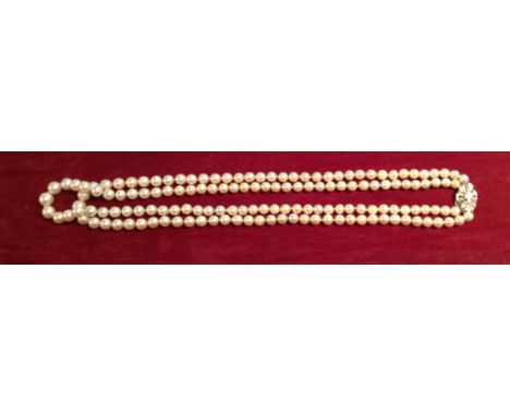 A 20TH CENTURY CULTURED PEARL AND DIAMOND NECKLACE Having two strands of graduated pearls, the yellow metal clasp set with ni