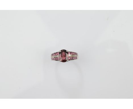 A certificated 9ct gold rhodolite garnet dress ring, central mixed cut in claw setting with channel set shoulders all in whit