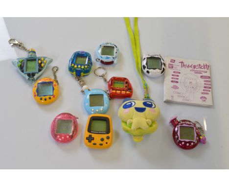 A collection of six Tamagotchis, in pink, yellow, white, and blue together with a Nintendo Pokémon Pikachu example, two Giga 