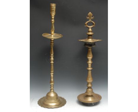 A large Indian brass candlestick, cylindrical sconce above a broad drip pan, domed lotus shaped base, 70cm high, 19th century