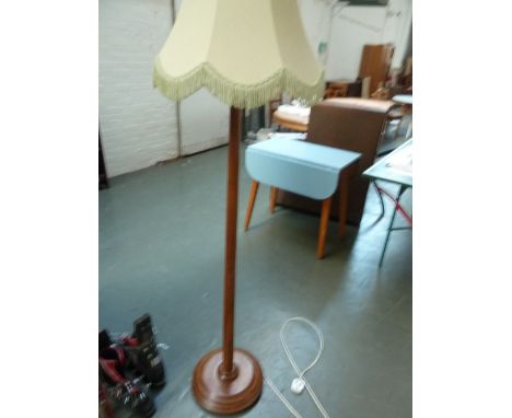 A wooden standard lamp with turned base and shade