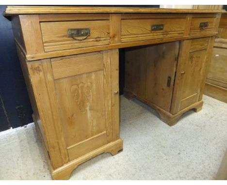A waxed pine double pedestal desk of three drawers over two cupboard doors on bracket feet