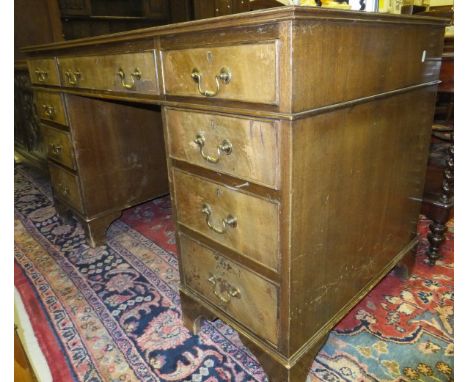 A mahogany pedestal desk of nine drawers with brass handles, on bracket feet, with green tooled leather top