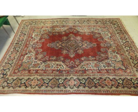 A Persian carpet, the central floral decorated medallion in shades of pale red, cream, taupe and dark blue, on a pale red flo