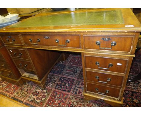 A reproduction yew wood veneered pedestal desk with a rectangular top with leather insert and central drawer flanked by two s