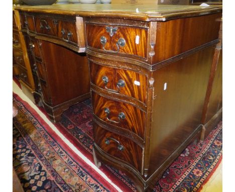 A reproduction mahogany pedestal desk, the shaped top with tooled and leather insert above a central drawer, flanked by two s
