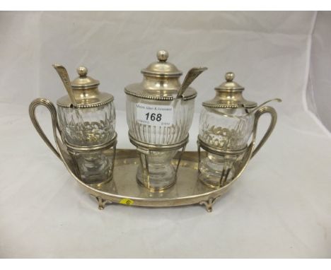 A George III silver cruet stand of boat shaped form, raised on four pad feet, set with three associated cut glass bottles and