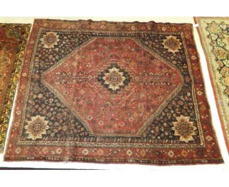 An early 20th Century Persian carpet with red ground centre medallion with floral, bird and animal motifs within a dark brown