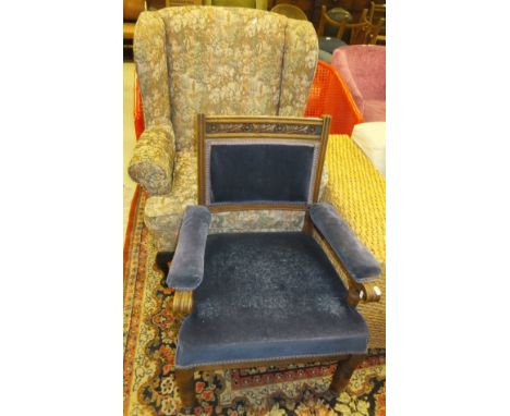 An Edwardian oak framed salon elbow chair with floral and foliate carved decoration upholstered in blue velvet type fabric, a