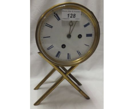 A brass bodied mantel clock with eight day movement and blue Roman numerals to the enamelled dial, raised on a brass stand 