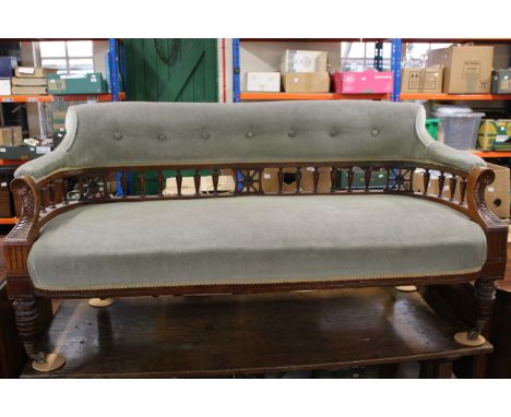 A Victorian mahogany salon sofa with upholstered back and seat, spindle turned gallery, on baluster tapering legs with brass 