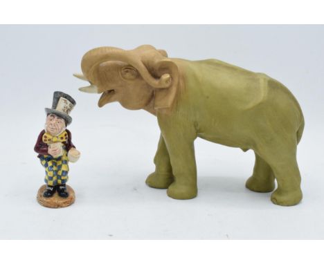 A Royal Dux (or similar) model of an elephant with trunk raised and numerals impressed in the stomach together with a Beswick