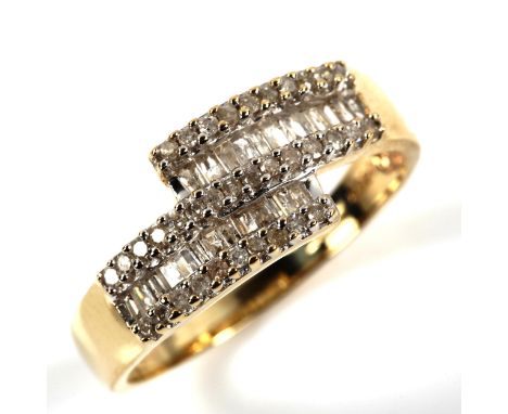 A modern 9ct gold diamond cluster crossover ring, set with baguette and round brilliant-cut diamonds, total diamond content a