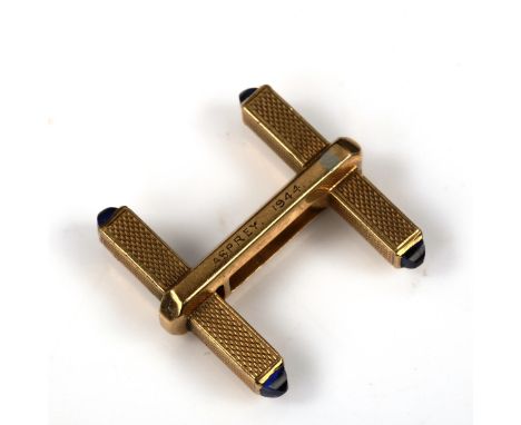 ASPREY - an Art Deco 9ct gold sapphire single cufflink, allover engine turned decoration with pyramid-cut cabochon terminals,