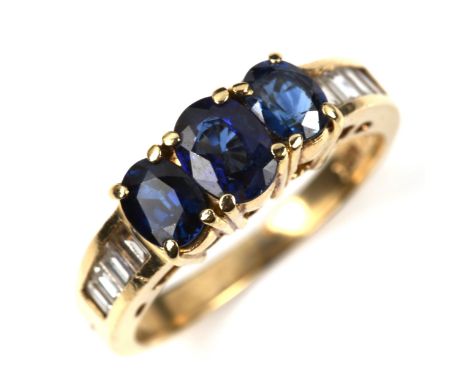 A 14ct gold sapphire and diamond dress ring, set with oval mixed-cut sapphire and baguette-cut diamond shoulders, setting hei