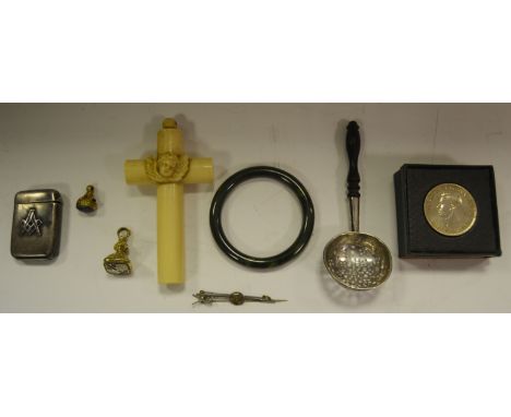 A Chinese spinach jade bangle; yellow metal fob, 19th Century; another; an early 20th Century silver tea strainer, ebony hand