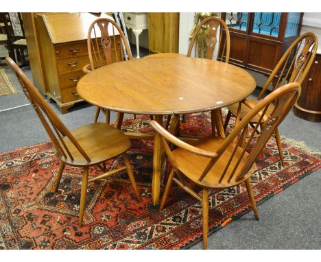 An Ercol drop leaf dining table; five conforming stick back Ercol dining chairs including two carver, pierced carving of a sw