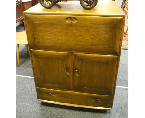 An oak Ercol Windsor cabinet, fall front cupboard above two panelled doors enclosing two shelves, one long drawer, caster fee