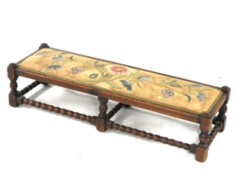 A long oak footstool, with bobbin turned stretchers and a crewel work seat, 100cm long