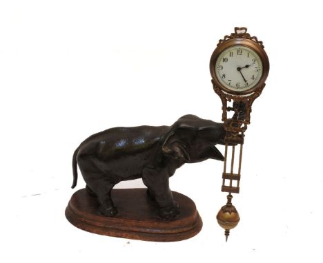 A Spelter Mystery clock, modelled as an elephant holding the clock and pendulum on its trunk, 28cm high, on stained wood plin