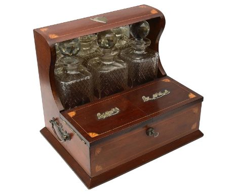 An Edwardian Sheraton Revival mahogany three bottle Tantalusinlaid with fan patterae, the mirror backed superstructure enclos