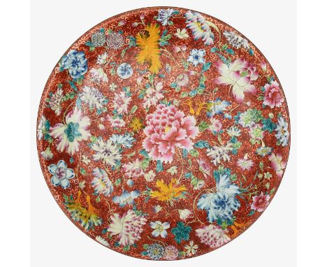 A 19th century Chinese famille rose millefleurs porcelain chargerpainted with peony, chrysanthemum and other blooms on a red 