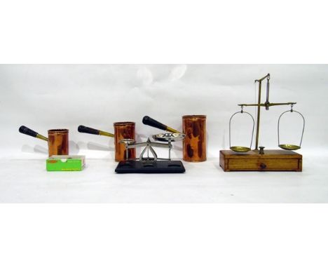 Three graduated copper measures of cylindrical form with turned wooden handles, a pair of brass balance scales on wooden base