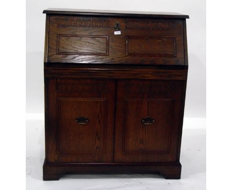 20th century oak bureau, the carved fall enclosing pigeonholes and drawer, with pair panel cupboards below enclosing shelf, o