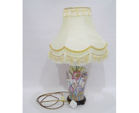 Moorcroft style ceramic lamp with irises, on a white ground and a fringed lamp shade 