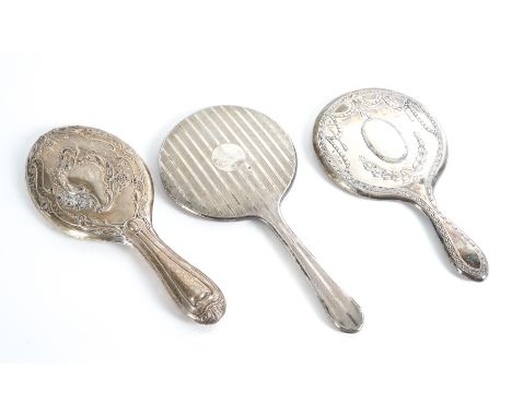 THREE LADY'S SILVER MOUNTED HAND MIRRORS (3)Comprising two with floral, foliate and scroll decoration, Birmingham 1905 and Bi
