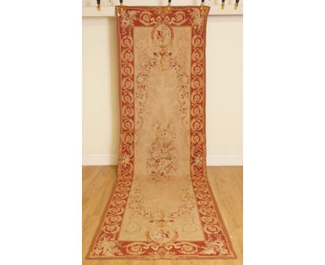AN AUBUSSON STYLE WOVEN RUNNERSecond half 20th Century 
In various coloured wools, the central panel with floral cartouche, b