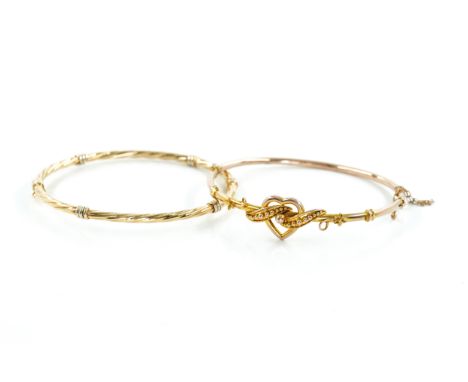 TWO 9CT GOLD BANGLES (2)Comprising; an Edwardian bangle, the front with a heart and beaded scroll motif, on a snap clasp, det