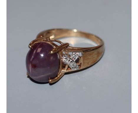 A 9k yellow metal and cabochon star ruby dress ring, with diamond chip set shoulders, size N.