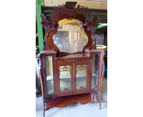 A late Victorian mahogany drawing room Cabinet, the upper section with a shaped bevelled plate within a fret carved surround,